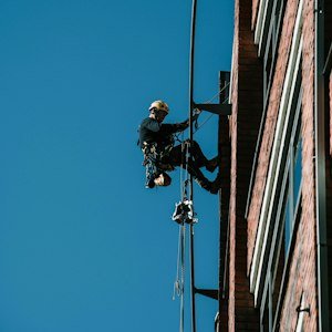 Rope access worker cleaning building facade - Work at Height